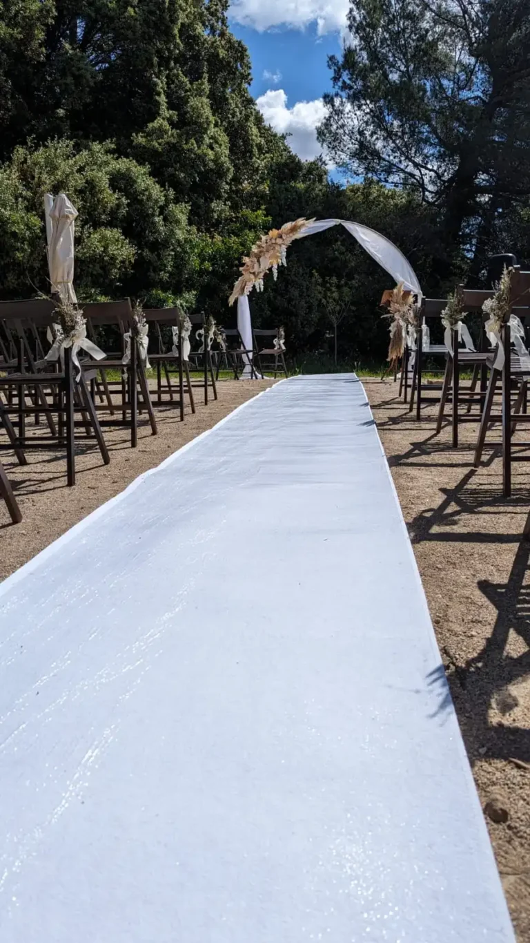 Allée de cérémonie avec moquette blanche épaisse, chaises en bois de mariage et arche ronde xxl