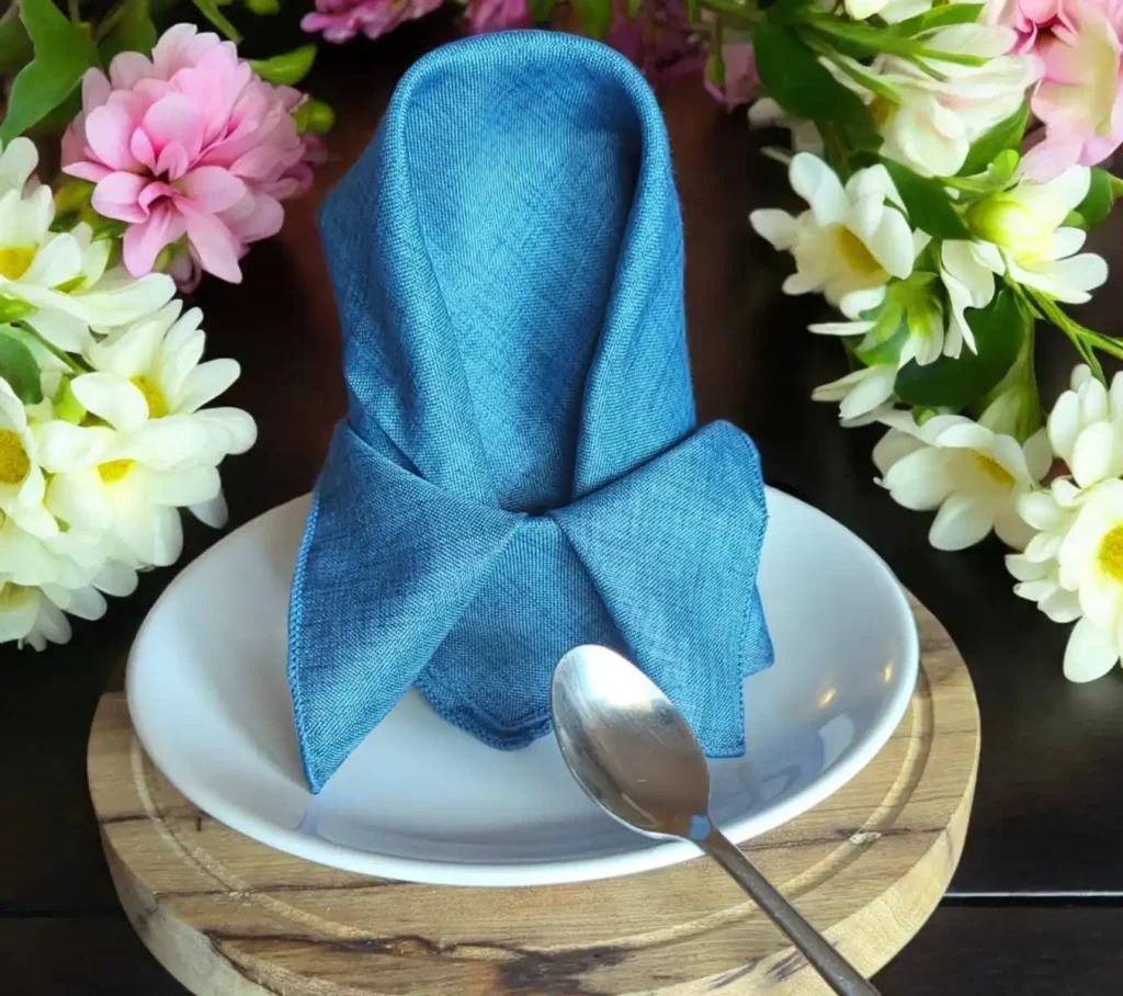 Location serviette bleu roi pour mariage, jolie serviette bleu roi en polyestere présenté avec un beau pliage dans un assiette blanche