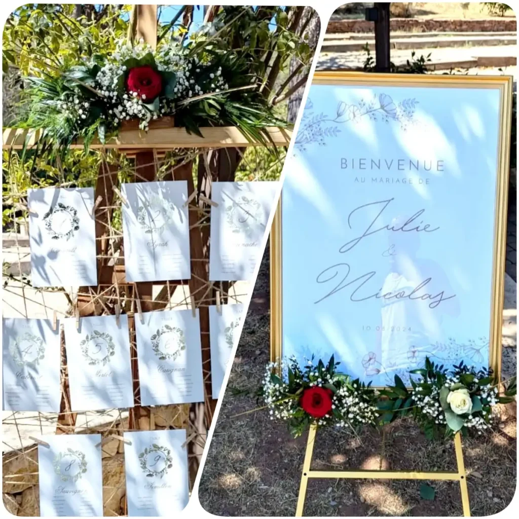 Panneau de bienvenue au mariage de Julie et Nicolas avec une décoration florale composée de roses rouges et blanches, situé en extérieur dans un cadre champêtre. Plan de table de mariage suspendu sur une structure en bois, orné de feuillage et de fleurs, avec des cartes numérotées pour chaque table. Mariage en plein air dans le Var, avec une ambiance naturelle et élégante.