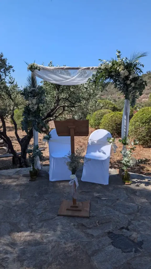 Location et installation de pupitre pour cérémonie de mariage au Domaine des Planes dans le Var, disponible chez Iliade Location. Arche décorée de fleurs et de voilage blanc, chaises blanches avec housses, cadre idyllique en plein air pour événements et mariages