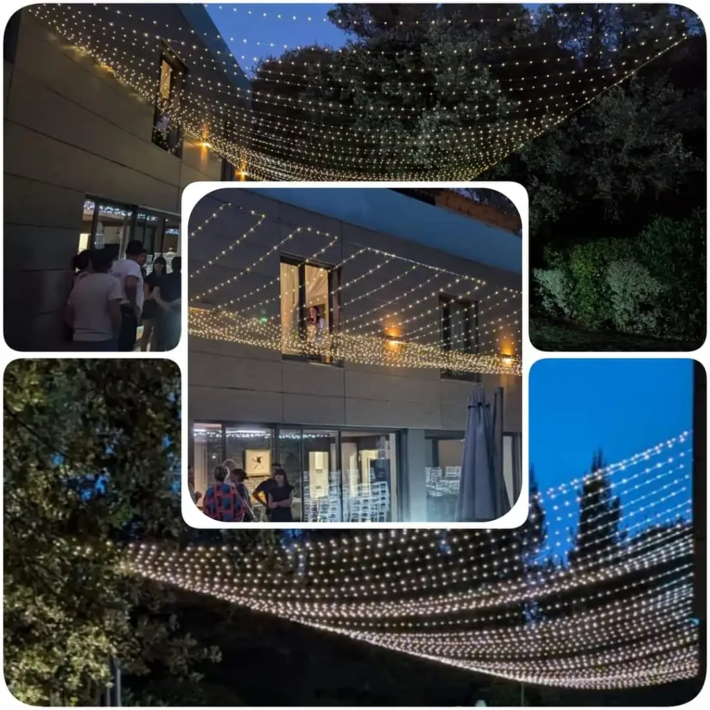 Une série de quatre images montrant une installation extérieure de guirlandes lumineuses suspendues, créant un effet de ciel étoilé. Les lumières blanches chaudes sont tendues au-dessus d'une terrasse et d'un bâtiment moderne, éclairant doucement la scène nocturne. Les invités se tiennent sous les lumières, discutant près de l'entrée, tandis que la façade vitrée reflète l'éclat des guirlandes. L'arrière-plan est constitué d'arbres sombres et d'un ciel nocturne dégagé.