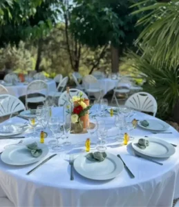 Matériel de mariage en location : Table de mariage en extérieur avec chaises blanches et décoration raffinée, illustrant un service de location chaises et tables mariage pour une réception élégante.