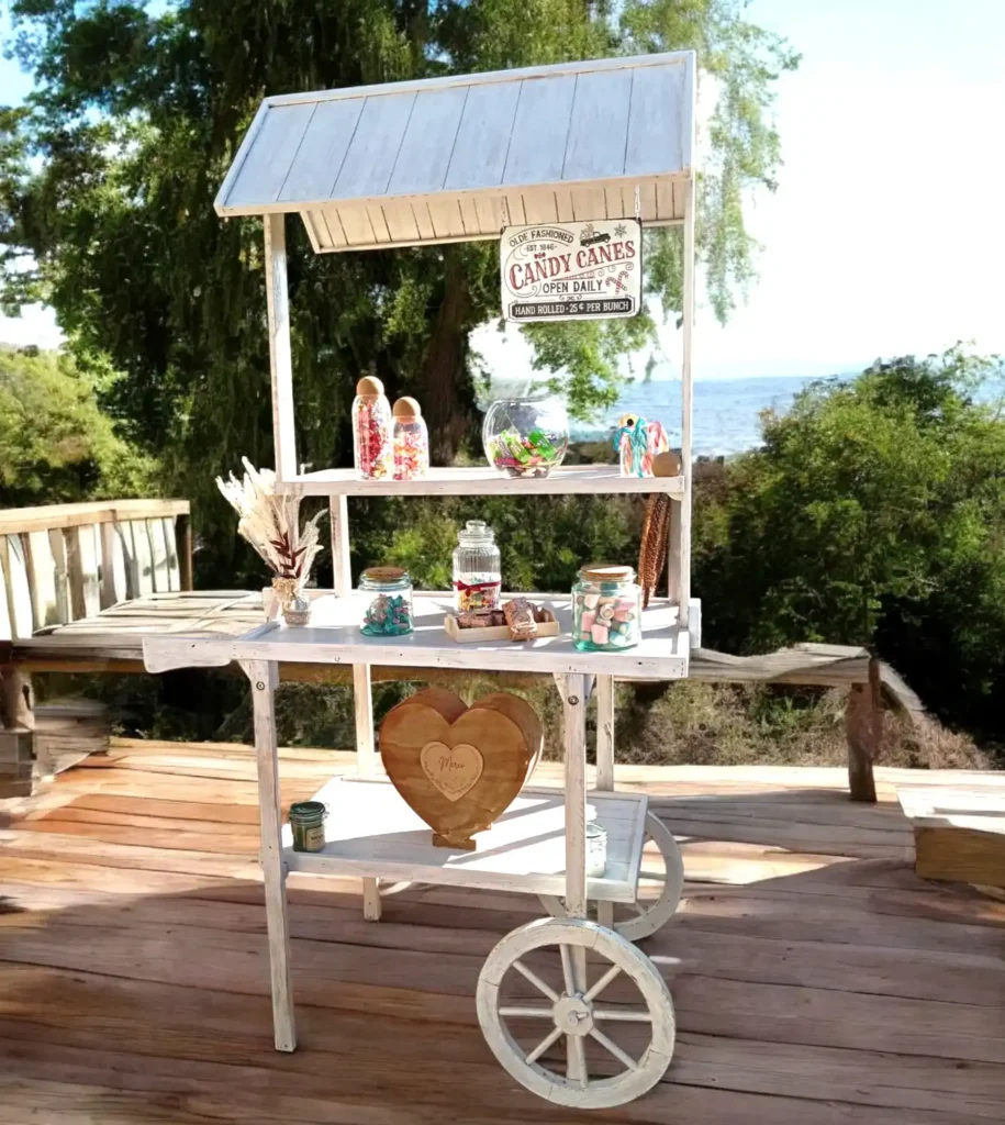 Candy bar blanc en bois pour mariage accompagné de ses contenaire à bonbons en verre.
