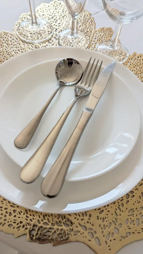 Kit vaisselle mariage complet en location dans le Var – assiettes blanches, couverts en inox et verres élégants sur napperon doré