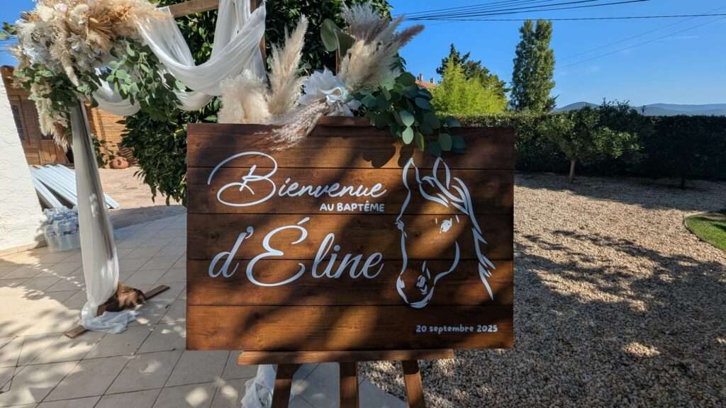 Panneau de bienvenue personnalisé en bois pour baptême à La Londe-les-Maures, orné de motifs floraux et d’une illustration de cheval, entouré de pampas et eucalyptus.