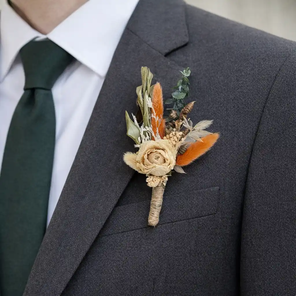 Boutonnière homme mariage en fleurs séchées fixée sur costume au niveau du pectoral gauche