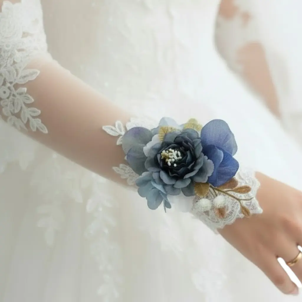 Bracelet mariée avec fleurs bleues porté sur robe de mariage en dentelle
