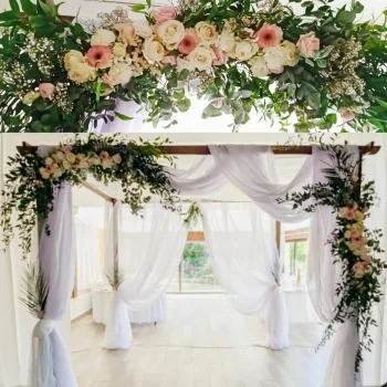 Gros plan sur la composition florale romantique d’une houppa, avec roses blanches, roses pâles, gypsophile et feuillage vert, sur fond de voile blanc.