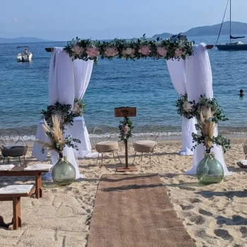 Arche de mariage houppa installée sur la plage du Coco Beach La Fossette dans le Var, décoration florale romantique avec voilage blanc.